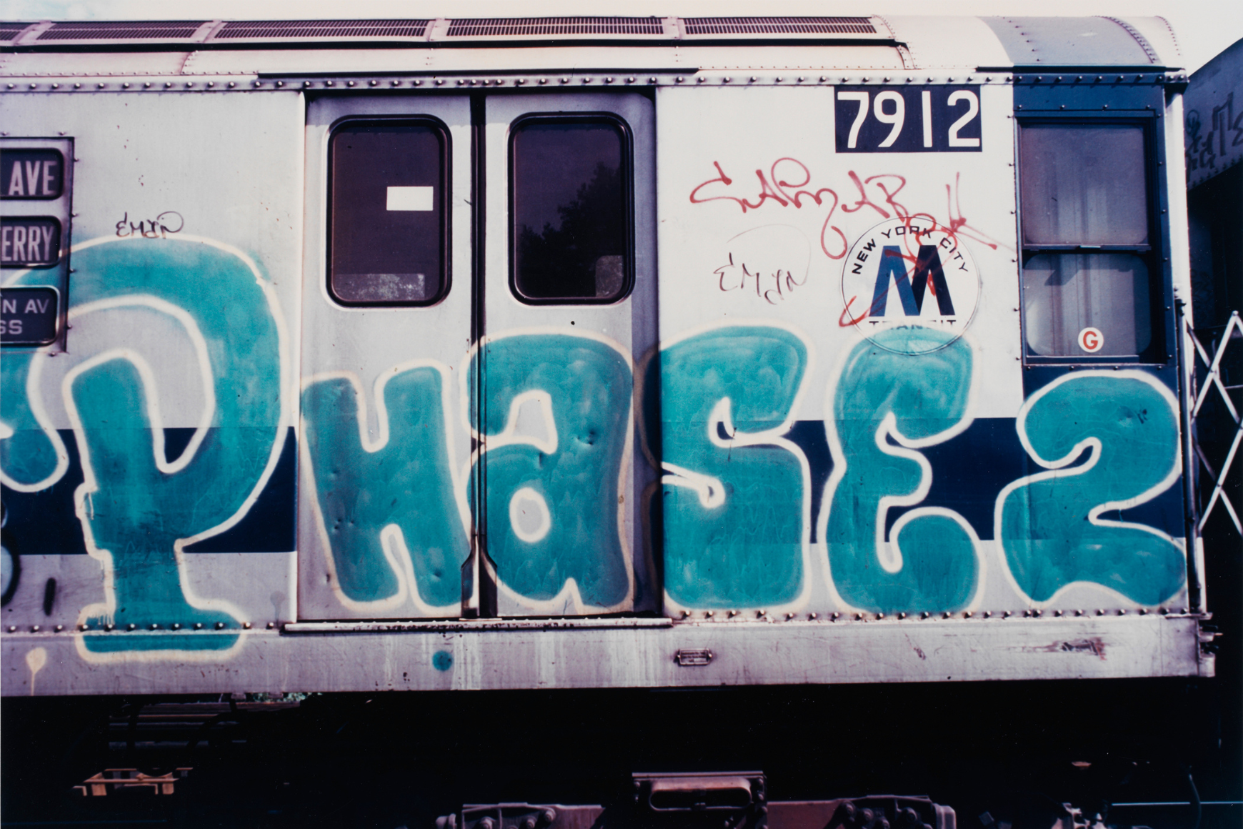 Image of graffiti writing on a subway train car above raised tracks 